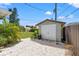 White double-door shed in backyard with gravel driveway at 7162 Benson St, Englewood, FL 34224