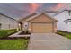 Tan house with a two-car garage and landscaping at 5552 Logan Cave Ave, Wimauma, FL 33598