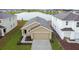 Tan house with a two-car garage, landscaped yard and lake view at 5552 Logan Cave Ave, Wimauma, FL 33598