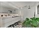 Modern bathroom featuring dual sinks, geometric tile floor, walk-in shower, and leafy green plants at 440 64Th Ave, St Pete Beach, FL 33706