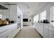Long kitchen with white cabinets and appliances leads to an open-plan living area at 440 64Th Ave, St Pete Beach, FL 33706