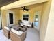 Relaxing covered patio with ceiling fan, comfortable seating, and access to the backyard at 1495 Robwood Ter, North Port, FL 34288