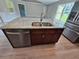 Kitchen island with granite countertop, double sink, and dishwasher at 1495 Robwood Ter, North Port, FL 34288