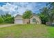 Tan house with white garage door and a well-manicured lawn at 1950 Lillian Ave, Tarpon Springs, FL 34689