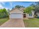 Two-story home with a white garage door and brick driveway at 1950 Lillian Ave, Tarpon Springs, FL 34689