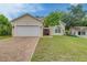 Tan two-story house with a white garage door and landscaped lawn at 1950 Lillian Ave, Tarpon Springs, FL 34689