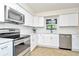 Updated kitchen featuring white cabinets, stainless steel appliances, and tile backsplash at 10617 N 27Th St, Tampa, FL 33612