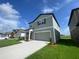 Two-story house with gray siding, two-car garage, and a landscaped lawn at 35182 White Water Lily Way, Zephyrhills, FL 33541