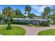 Attractive mid-century home with circular driveway, lush landscaping, and palm trees at 3903 Belle Vista E Dr, St Pete Beach, FL 33706