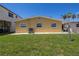 Home's rear exterior with a grassy yard, white stone accents, and visible AC unit at 704 180Th E Ave, Redington Shores, FL 33708