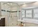 Clean bathroom with a glass enclosed shower, a soaking tub and plantation shutters at 19820 Gulf Blvd # 401, Indian Shores, FL 33785