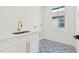 Bright laundry room with white cabinets, a modern sink, and decorative tiled flooring at 135 48Th Ave, St Petersburg, FL 33703