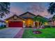 Inviting home exterior with a two-car garage, green lawn, and lush landscaping at dusk at 957 Westwinds Blvd, Tarpon Springs, FL 34689