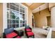 Front porch with wicker chairs and red cushions, offering a relaxing outdoor space at 957 Westwinds Blvd, Tarpon Springs, FL 34689