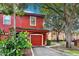 Red two-story townhome with attached garage and lush landscaping, located in a tree-lined community at 2272 Chianti Pl # 4-0048, Palm Harbor, FL 34683