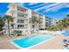 Community pool with building view and lounge chairs at 19610 Gulf Blvd # 308, Indian Shores, FL 33785