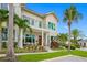 Tan two-story house with palm trees, a balcony, and a manicured lawn at 6 Hibiscus Ln, Belleair, FL 33756