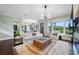 Bright living room with a large white sofa, statement chandelier, and hardwood floors at 6 Hibiscus Ln, Belleair, FL 33756