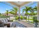 Relaxing covered porch with wicker seating and view of palm trees at 6 Hibiscus Ln, Belleair, FL 33756