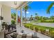 Covered porch with wicker seating, offering a view of the street and palm trees at 6 Hibiscus Ln, Belleair, FL 33756