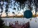 A red wood deck on the water with 4 white chairs, and a teal lantern hanging from a tree at 1964 Arvis E Cir, Clearwater, FL 33764