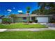 Charming home featuring a manicured lawn, palm trees, and a two-car garage at 10799 Harborside Dr, Largo, FL 33773