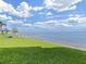 Expansive backyard featuring manicured lawn leading to a serene bay with a charming wooden pier under a cloudy sky at 6177 Sun Blvd # 108, St Petersburg, FL 33715