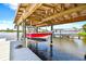 Covered boat lift holding a red and white boat, with two boat slips at 644 Bayshore Dr, Tarpon Springs, FL 34689