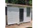 View of shed exterior featuring white siding and a door, nestled beside a red brick pathway at 8665 Mockingbird Ln, Seminole, FL 33777
