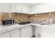 Small galley kitchen with white cabinets and tile backsplash at 4001 58Th N St # 16, Kenneth City, FL 33709