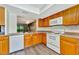 Kitchen features wood cabinets, white appliances, and wood-look floors at 103 Brigadoon Dr, Clearwater, FL 33759