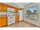 Kitchen boasts wood cabinets, white appliances, and a large window at 103 Brigadoon Dr, Clearwater, FL 33759