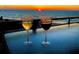 Sunset view from a balcony with two glasses of wine, offering a serene and relaxing ambiance at 2618 Gulf Blvd # 505, Indian Rocks Beach, FL 33785