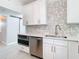 Modern white kitchen with stainless steel appliances and geometric backsplash at 161 Overbrook W St, Largo, FL 33770
