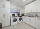 Bright laundry room with white cabinets, front load washer and dryer, and a sink at 540 N Tamiami Trl # 1702, Sarasota, FL 34236