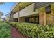 Exterior view of condo building showcasing brick and wood siding with landscaping at 36750 Us Highway 19 # 23-110, Palm Harbor, FL 34684