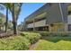 Exterior of condo building with landscaping and brick facade at 36750 Us Highway 19 # 23-110, Palm Harbor, FL 34684