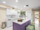 Modern kitchen with white cabinets, purple island, and mosaic backsplash at 20051 Gulf Blvd, Indian Shores, FL 33785