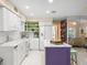 Modern kitchen with white cabinets, purple island, and mosaic backsplash at 20051 Gulf Blvd, Indian Shores, FL 33785
