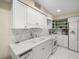 Bright white kitchen features marble backsplash and stainless steel appliances at 20051 Gulf Blvd, Indian Shores, FL 33785