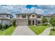 Two-story house with beige exterior, brown accents, and a three-car garage at 1821 Cherry Walk Rd, Lutz, FL 33558