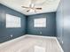 A well-lit bedroom with sleek, light-colored floors, blue accent walls, and a ceiling fan at 1433 S Belcher Rd # G10, Clearwater, FL 33764