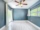 Well-lit bedroom with ceiling fan, sliding glass door and a large window, featuring stylish blue walls at 1433 S Belcher Rd # G10, Clearwater, FL 33764