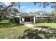 Ranch house with covered entry, mature trees, and manicured lawn at 10208 Grove Dr, Port Richey, FL 34668