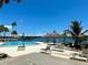 Inviting pool area with waterfront views, lounge chairs, and thatched umbrellas at 7200 Sunshine Skyway S Ln # 7E, St Petersburg, FL 33711