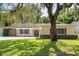 Charming home featuring well-manicured lawn, mature trees, and distinctive architectural details at 12912 Willoughby Ln, Hudson, FL 34667