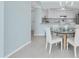 Open-concept dining and kitchen area featuring white cabinets and a modern glass table set for dining at 6 Belleview Blvd # 706, Belleair, FL 33756