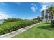 Scenic walking path with lush green foliage and palm trees in front of condo building with water views at 6 Belleview Blvd # 706, Belleair, FL 33756
