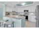 Modern kitchen with white cabinetry, stainless steel appliances, and a stone countertop island with seating at 6 Belleview Blvd # 706, Belleair, FL 33756
