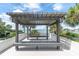 Tranquil patio view of the water and surrounding greenery, framed by a shaded pergola with seating at 6 Belleview Blvd # 706, Belleair, FL 33756